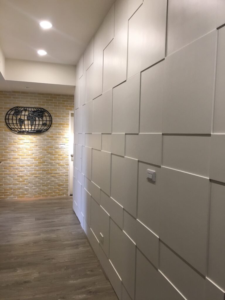 現代風走廊設計，右側為白色塊狀幾何造型牆，盡頭是黃色文化石端景與世界地圖裝飾。